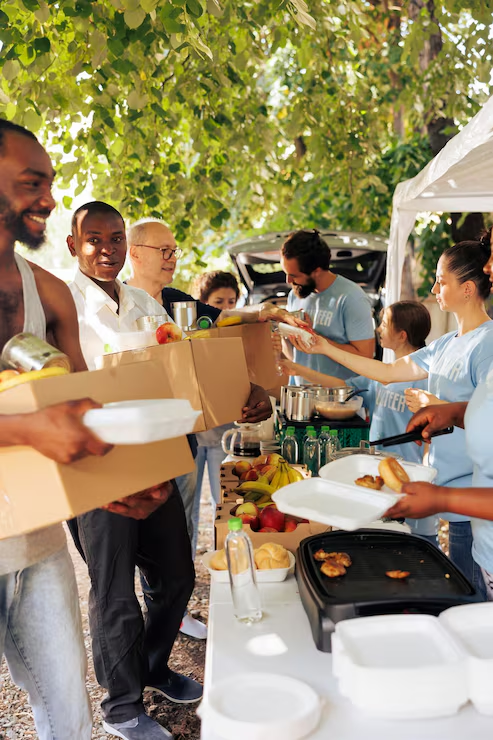 Volunteers and neighbors sharing boxed groceries and meals outdoors