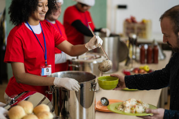 Volunteer smiling while serving a meal from a large pot